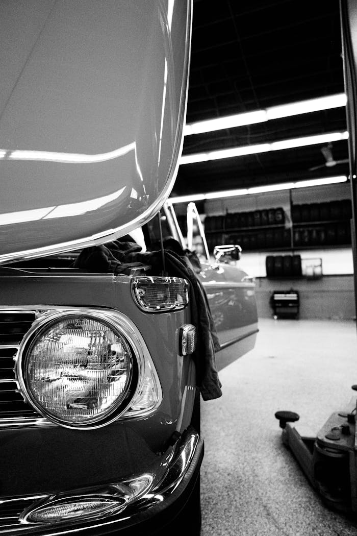 Classic BMW with hood open in a repair garage. Black and white image highlighting automotive design.